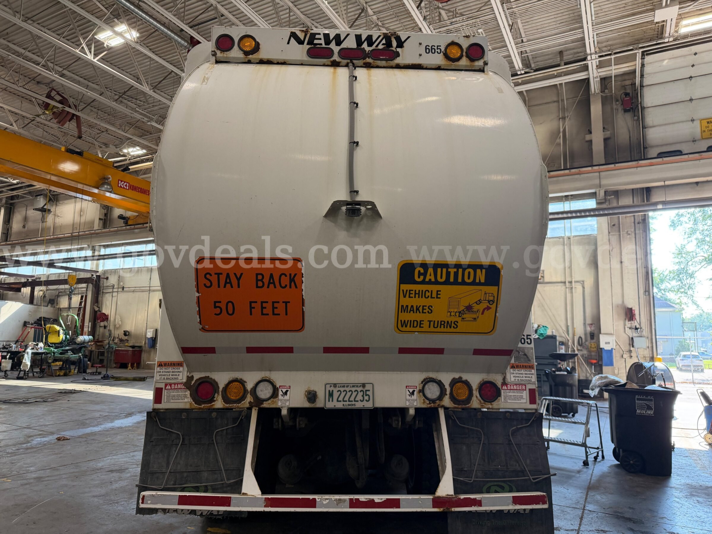 Back of 2019 Peterbilt 520 garbage truck showing New Way at top, caution signs: Stay Back 50 Feet and Vehicle Makes Wide Turns, license plate and rear lights.