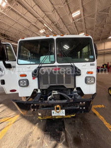 Peterbilt 520 garbage truck front view with grille, windshield, and bumper in a warehouse setting.