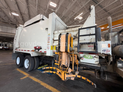 Peterbilt 520 garbage truck side view showing rear compactor and hydraulic lift system with yellow arms.