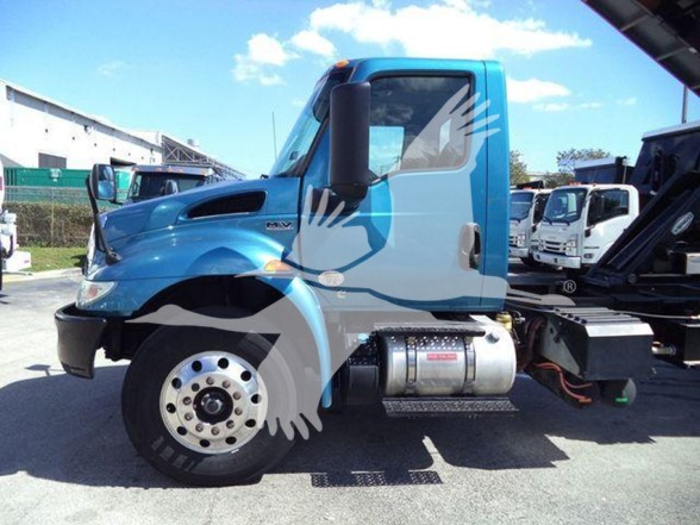 Truck cab side view of a blue 2020 International MV dump truck showing front wheel, fuel tank, and side steps.