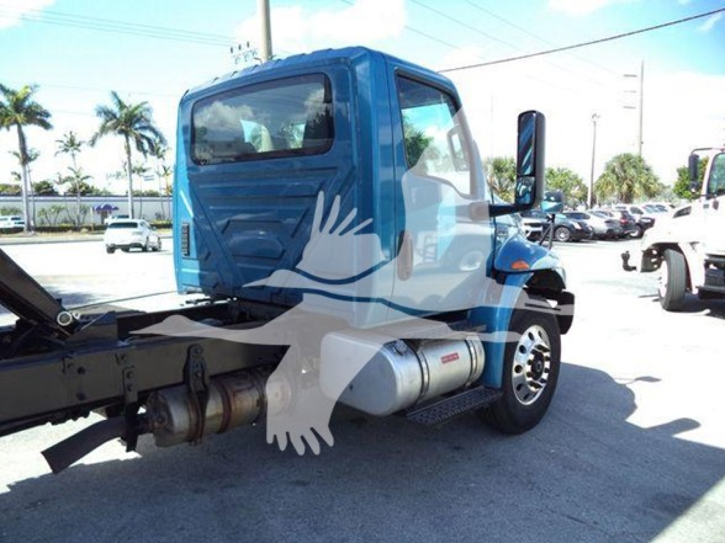 Blue 2020 International MV dump truck cab with side exhaust and fuel tank visible; rear view shows truck chassis and hitch.