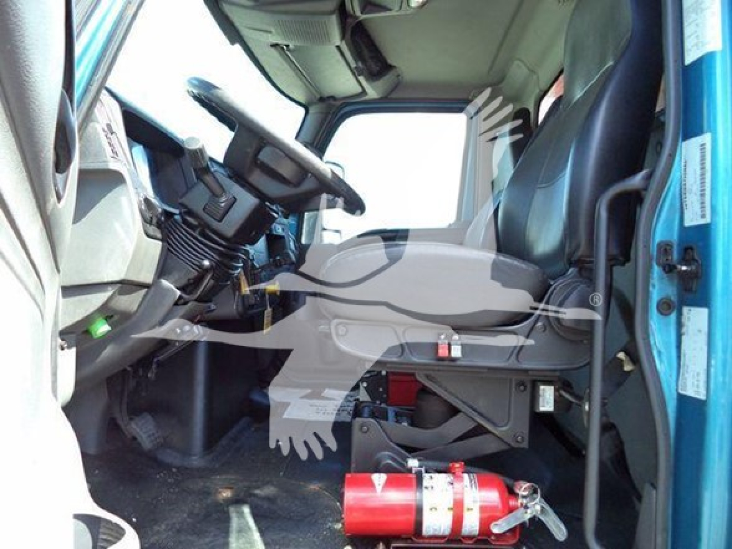 Truck cab interior of a 2020 International MV dump truck showing steering column, seat, and dashboard area.