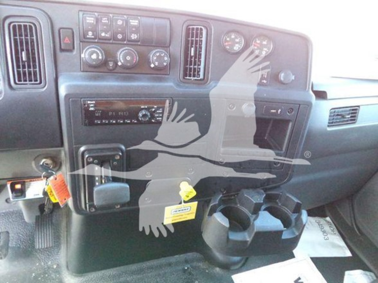Interior of a 2020 International MV dump truck dashboard showing steering wheel area, center console, gauges, climate controls, and cup holders.