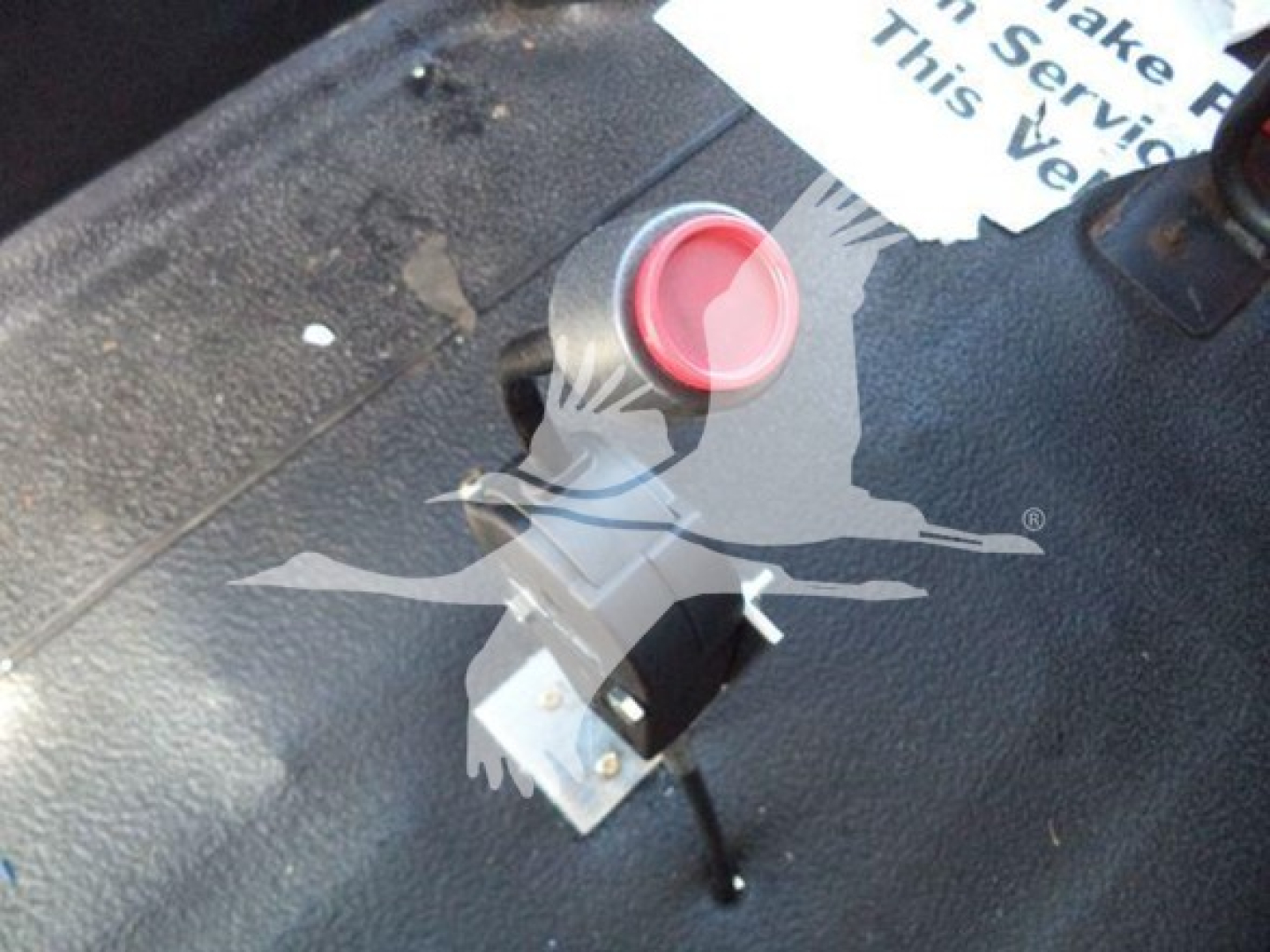 Control switch with red cap mounted on metal surface, part of truck equipment. Visible label reads '?', no other legible text.