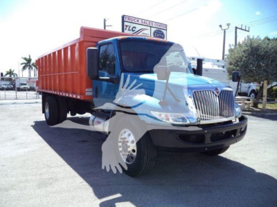 Dump truck front-left view showing blue cab with orange dump bed and International grille badge, VIN tag visible on windshield area.