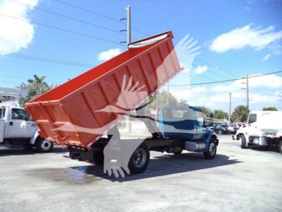 Dump truck with lifted red dump bed in a dealership lot, International MV series, stock number T51680.