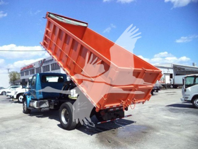 Dump truck from 2020 International MV with orange dump bed raised, blue cab, in a truck lot.