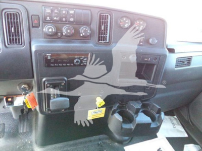Interior of a 2020 International MV dump truck dashboard showing steering wheel area, center console, gauges, climate controls, and cup holders.