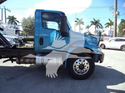 Truck cab side view of a blue and white International MV dump truck showing front wheel and fuel tank with stock number T51680.