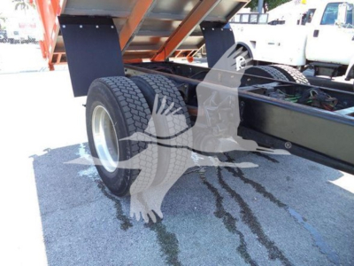 Truck rear axle area of a 2020 International MV dump truck showing dual rear wheels and chassis with hydraulic lines; part of dump body elevated.