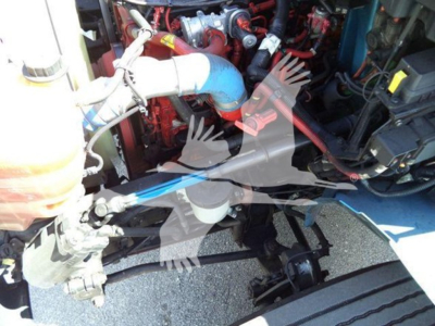 Dump truck engine bay from a 2020 International MV showing large blue hose, red engine components, and various wiring in view.