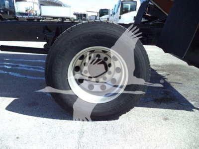 Trailer wheel and tire assembly shown under a dump truck chassis with rim and tire tread visible.