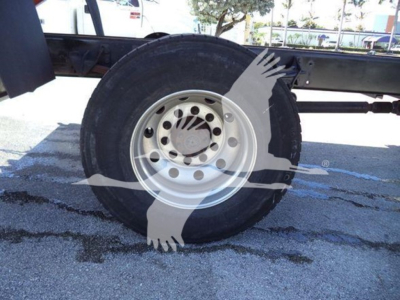 Truck wheel and tire on International MV dump truck chassis showing steel rim and hub with multiple lug holes.
