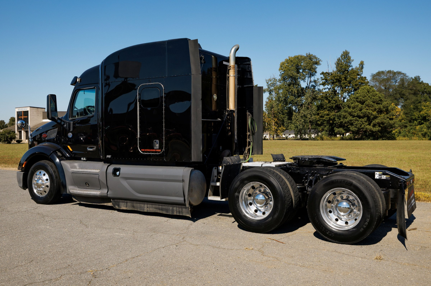 Peterbilt 579 conventional sleeper truck side view showing black exterior, dual rear axles, chrome wheels, and exhaust stack.
