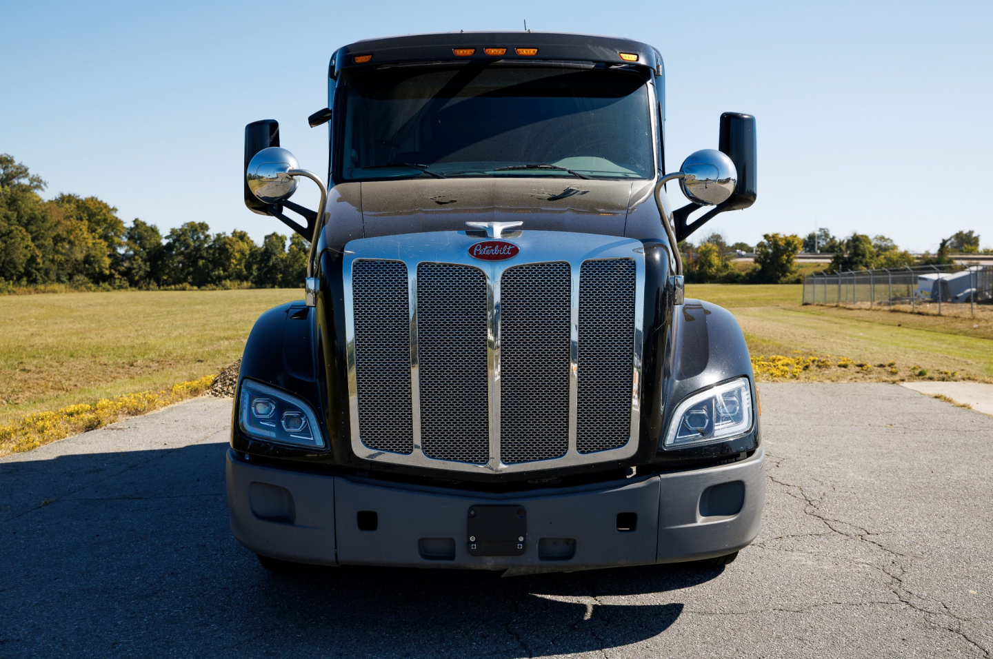 Peterbilt 579 conventional sleeper front view showing chrome grille, headlights, and bumper.