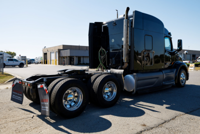 Peterbilt 579 tractor rear/side view showing dual rear axles and shiny chrome wheels, dark gloss cab, no trailer attached.