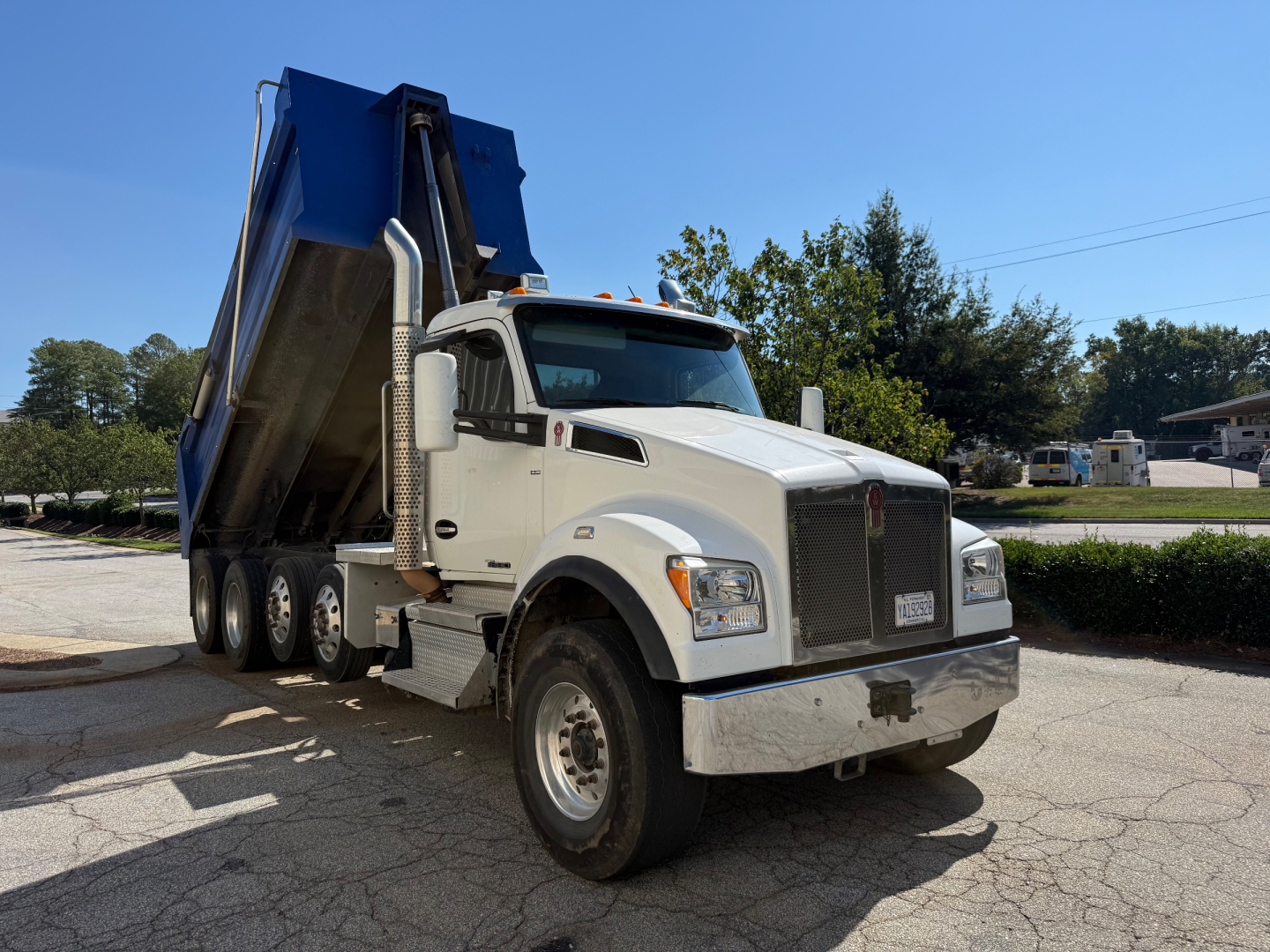 Kenworth T880 dump truck in-service showing white cab and blue dump body with front grille and side mirrors.