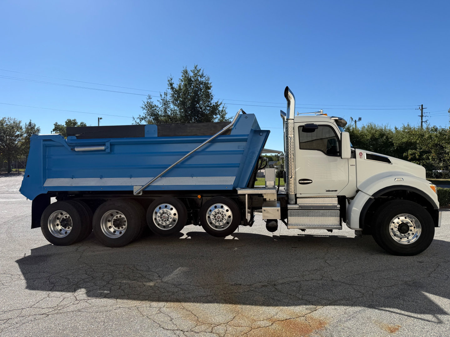 Kenworth T880 dump truck inSide view showing dump bed and 6-wheel axle configuration.