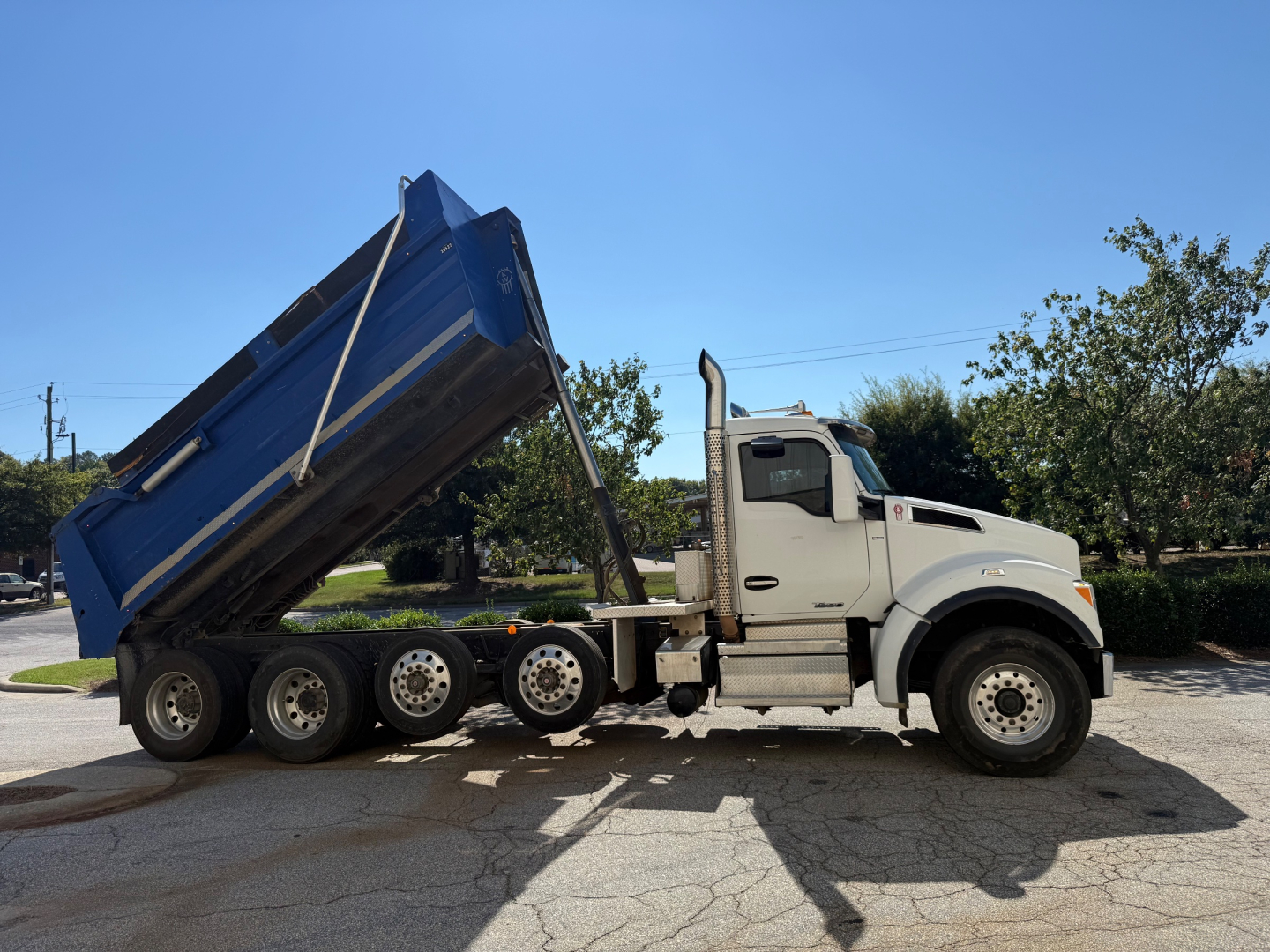Kenworth T880 dump truck with raised dump bed in side profile view showing dump hydraulics and rear wheels