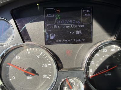 Dashboard cluster of a Kenworth truck showing digital display with odometer 208,226.2 miles, fuel economy, idle usage, and gauges for RPM and speed.