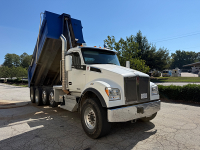 Kenworth T880 dump truck in-service showing white cab and blue dump body with front grille and side mirrors.