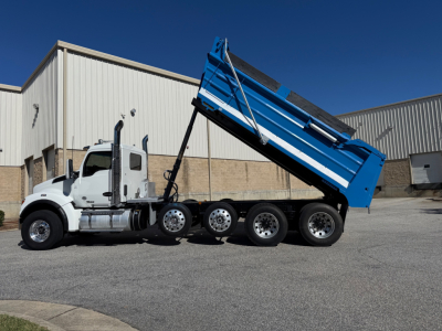 Kenworth T880 dump truck in-service showing white cab and blue dump bed with multiple axles in a parking lot.