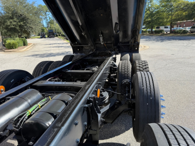 Kenworth T880 chassis with dump truck under raised bed showing dual rear axles and hydraulic components.
