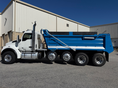 Kenworth T880 dump truck side view showing blue dump body and white cab with chrome fuel tanks and black tires.