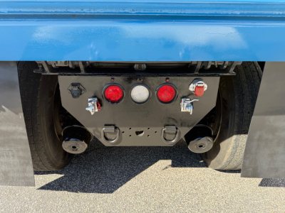 Kenworth T880 rear undercarriage showing a black metal mounting plate with red and white lights and two round towing/attachment points.