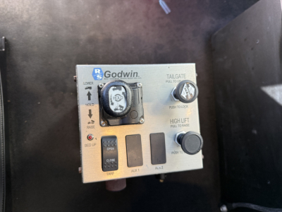 Kenworth truck dash view showing Godwin tailgate control panel with knobs and labels including ‘TAILGATE’, ‘LOWER’, ‘RAISE’, and ‘HIGH LIFT’ along with auxiliary switches.