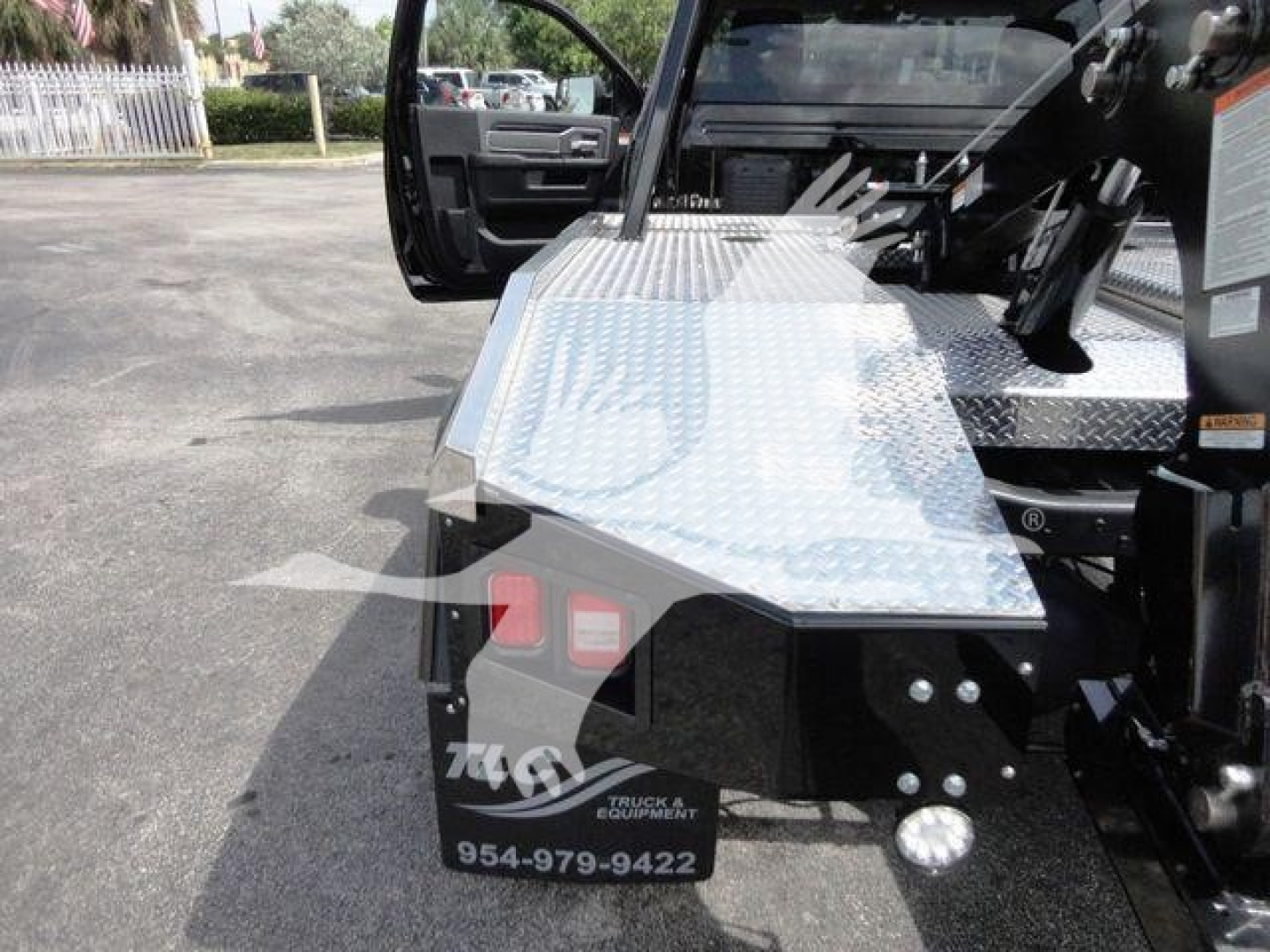 Ram 4500 HD SLT winch truck with diamond plate aluminum step and rear bumper, open driver door, showing 954-979-9422 contact and winch equipment.