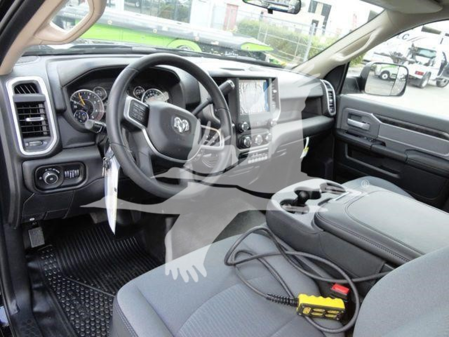 Ram 4500 interior with steering wheel and dashboard showing large touchscreen display and center console; winch-related equipment visible in foreground.