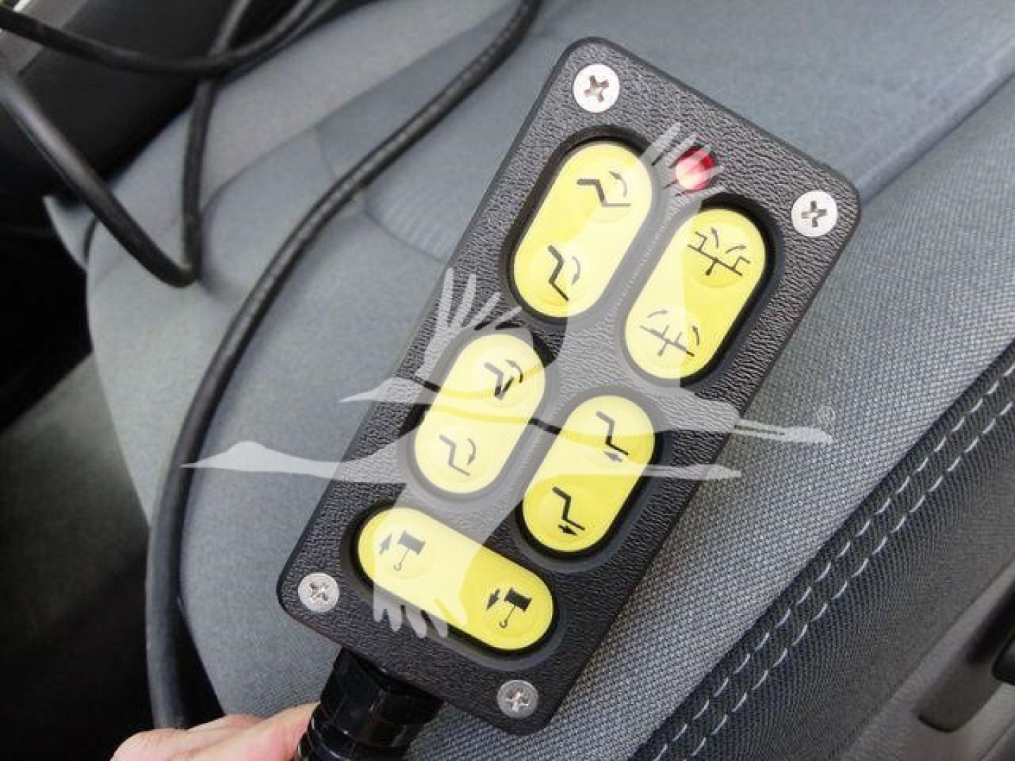 Winch remote with six yellow buttons mounted in vehicle interior view showing controls.