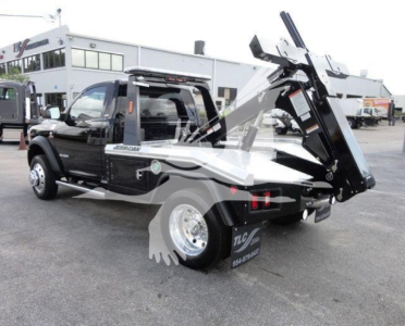 Ram 4500 chassis cab with heavy-duty tow/tilt bed and wheel-lift, black crew cab, in-service yard setting.