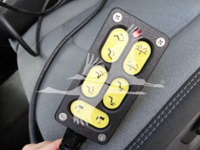 Winch remote with six yellow buttons mounted in vehicle interior view showing controls.