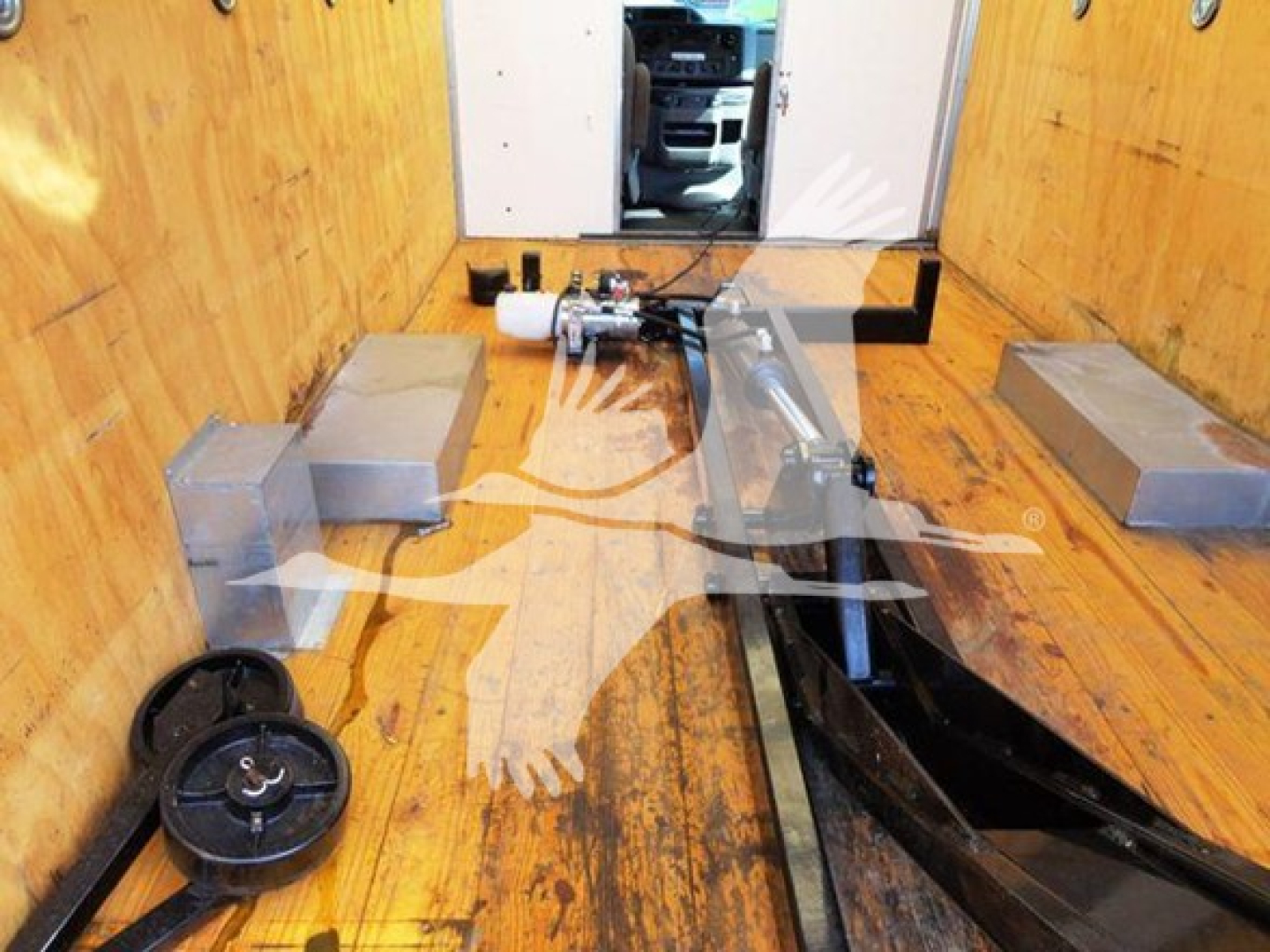 Truck interior showing cable winch and mounting hardware with wooden cargo bay, tiedowns, and side walls.