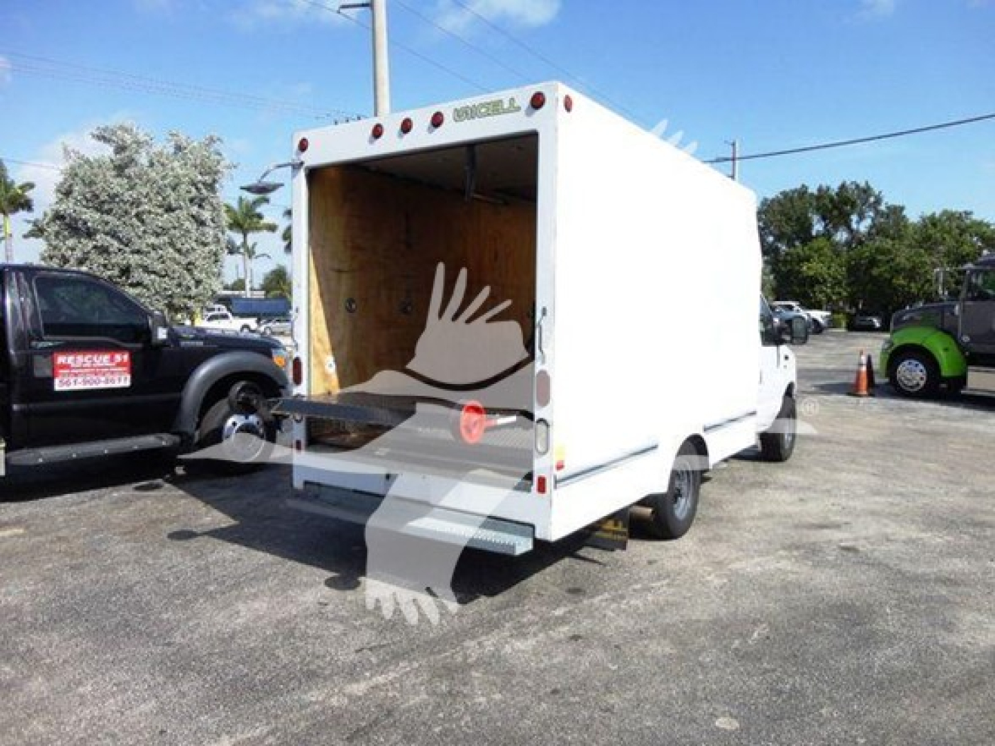Box truck with open rear cargo area showing interior walls, Ford E-350 cutaway box truck, white exterior, parked lot.