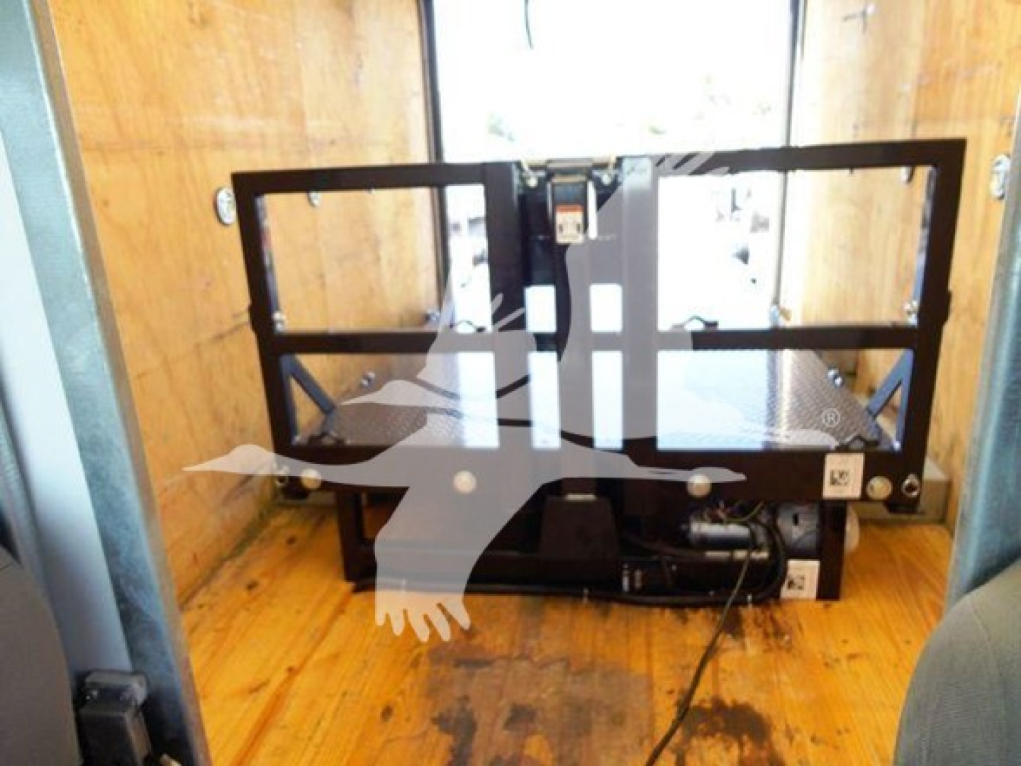 Equipment mounting frame inside cargo area with metal brackets and hydraulic connections; no readable labels visible.