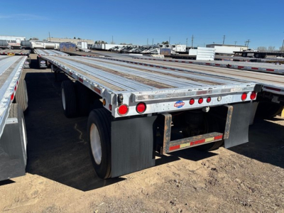 Flatbed trailer with dual rear wheels, aluminum deck, rear underride guard, and taillight cluster. Visible small circular reflectors and blemish-free surface with VIN/stock details not on image.