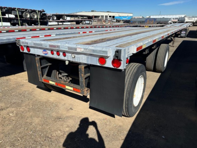Trailer rear view showing flatbed utility trailer with dual rear axles and reflective tape, license plate area, and mud flaps.