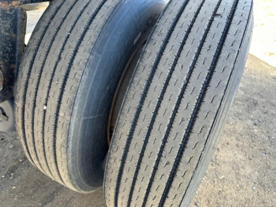 Two worn tandem trailer tires on a flatbed trailer showing tread grooves.