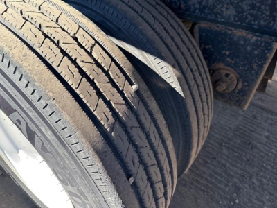 Dual tires on a utility flatbed trailer showing tread pattern and wheel well edge with blue frame.