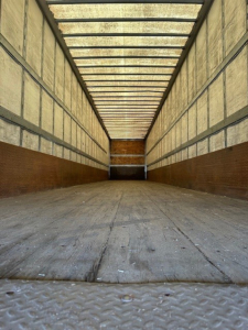 Trailer interior showing empty box trailer with wooden side walls and metal floor, long length, rear opening visible.