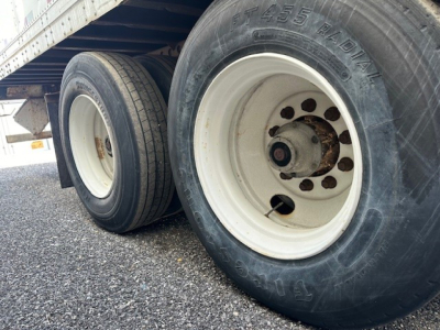 Image shows trailer wheels with dual tires, white rims, and visible tire sidewalls; part of a Strick Roll Door trailer in a used condition.