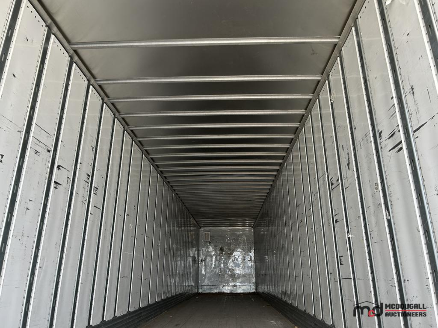 Interior of a 53' dry van trailer with metal walls and overhead rails, empty cargo area.
