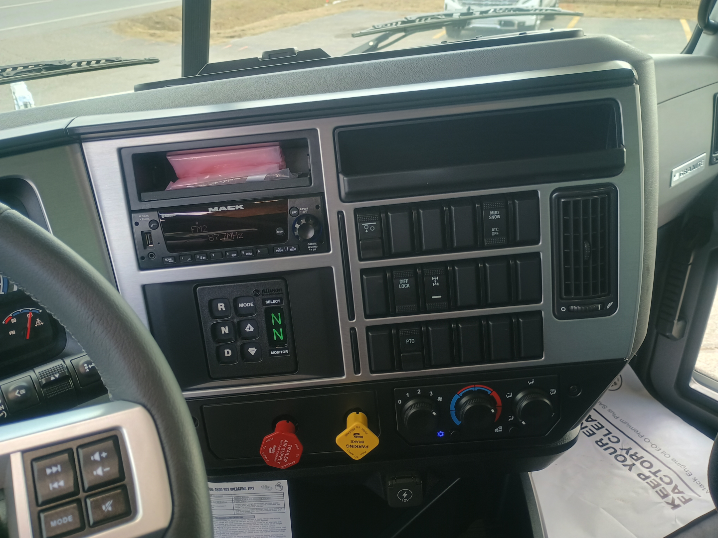 Dashboard of new Mack GR84F dump truck showing radio, climate controls, ignition area, and instrument panel.