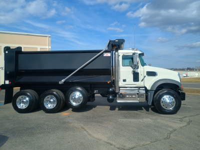  dump truck side view showing Mack GR84F chassis with black dump bed, chrome wheels, white cab, side steps, fuel tanks, and taillights.