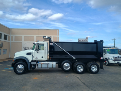 Dump truck side view showing 6-wheel rear with black dump body and white cab, Mack GR84F 2026 model visible in listing context.