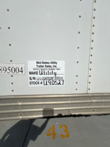 Trailer sticker on mid-sized utility van showing Mid-States Utility Trailer Sales, Inc. make unit, S/N U..., STOCK # U90527, 895004 label, metal side with rivets