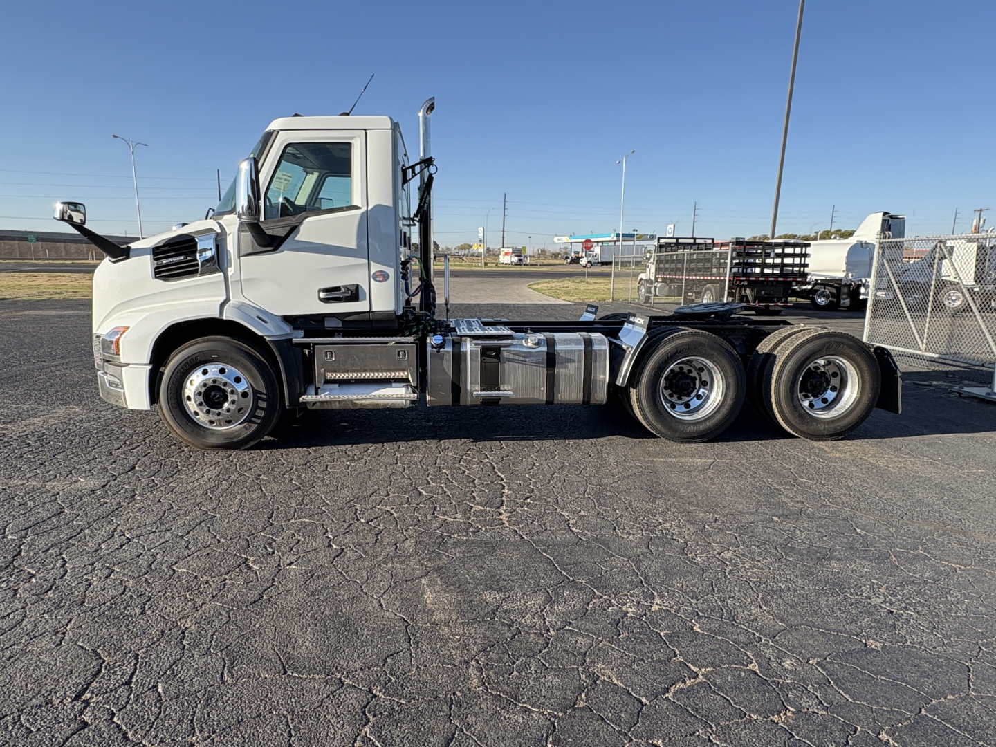 Conventional daycab truck side view showing Mack AN64T chassis and 6x4 rear axles with fuel tanks and ladder rungs.